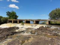 Barragem por onde a água escoa sobre o afloramento de rocha vulcano-sedimentar